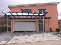 Carports in jeglicher Größe bieten Platz zum Unterstellen. Hier wurde Edelstahl mit pulverbeschichtetem Stahl kombiniert. Ein Regenablauf ist in die Dachfläche integriert.